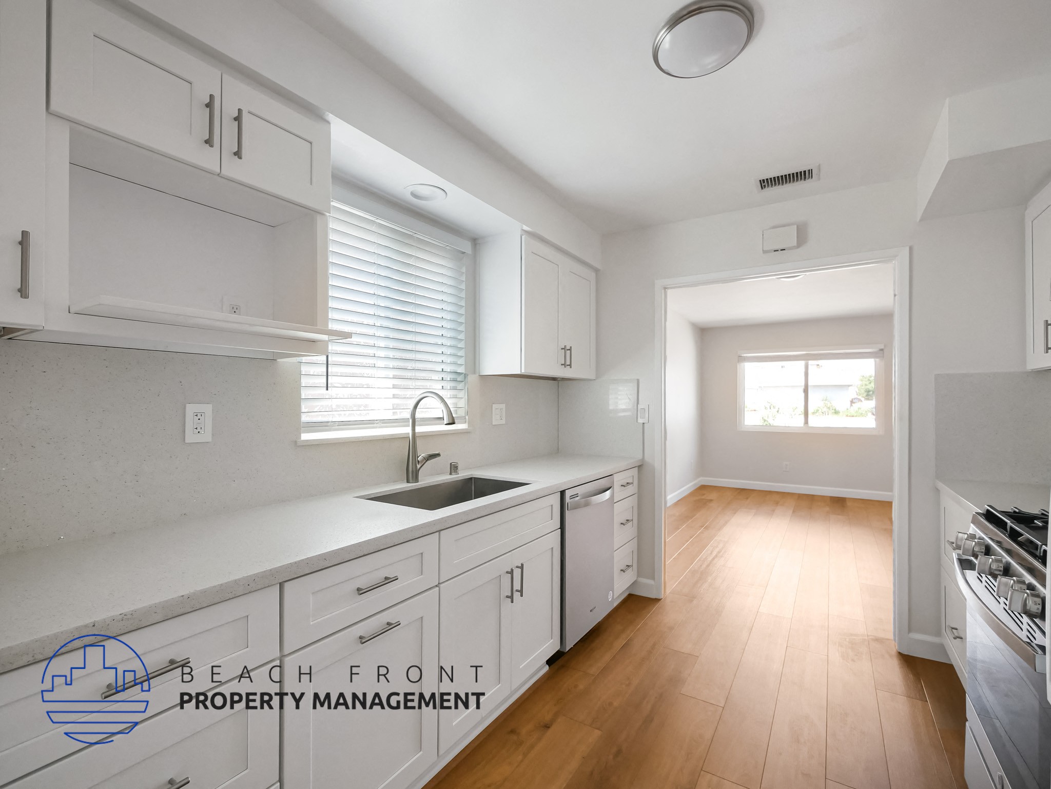 A kitchen with white cabinets and a wooden floor.